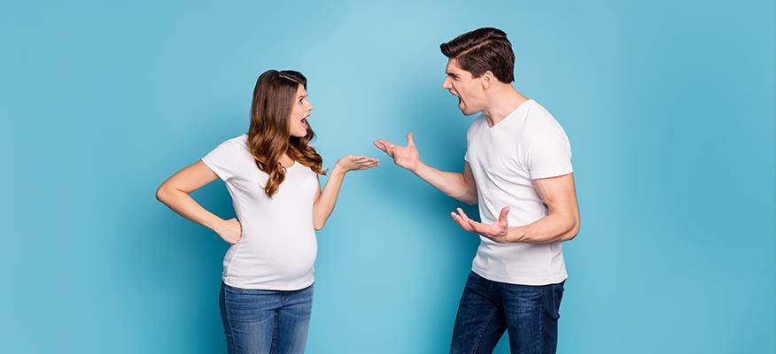 Pregnant couple talking and holding hands while dealing with relationship challenges.