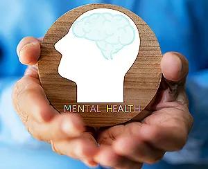 A person holding a wooden circle with a brain icon, symbolizing awareness of what is mental health.