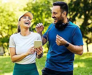 Happy sports couple laughing while exercising outdoors, showing how to maintain a healthy lifestyle together.
